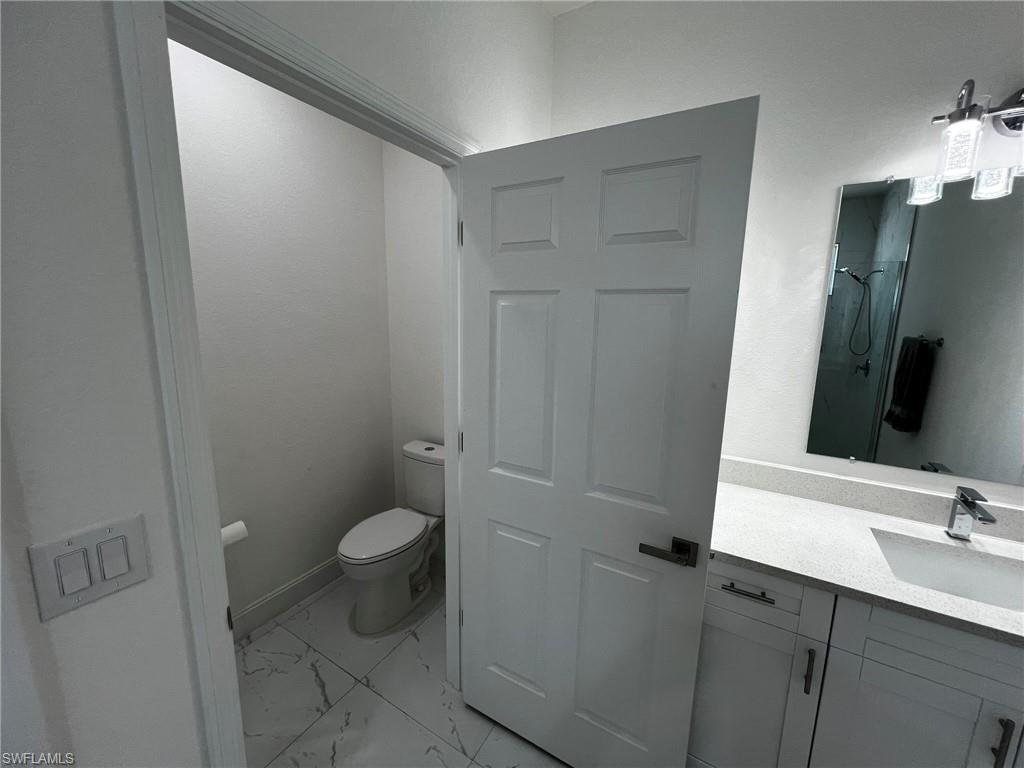 3313 68th Street West Lehigh Acres, FL 33971 - Photo 20 of 26 Full bath with a shower, marble finish floor, vanity, and toilet