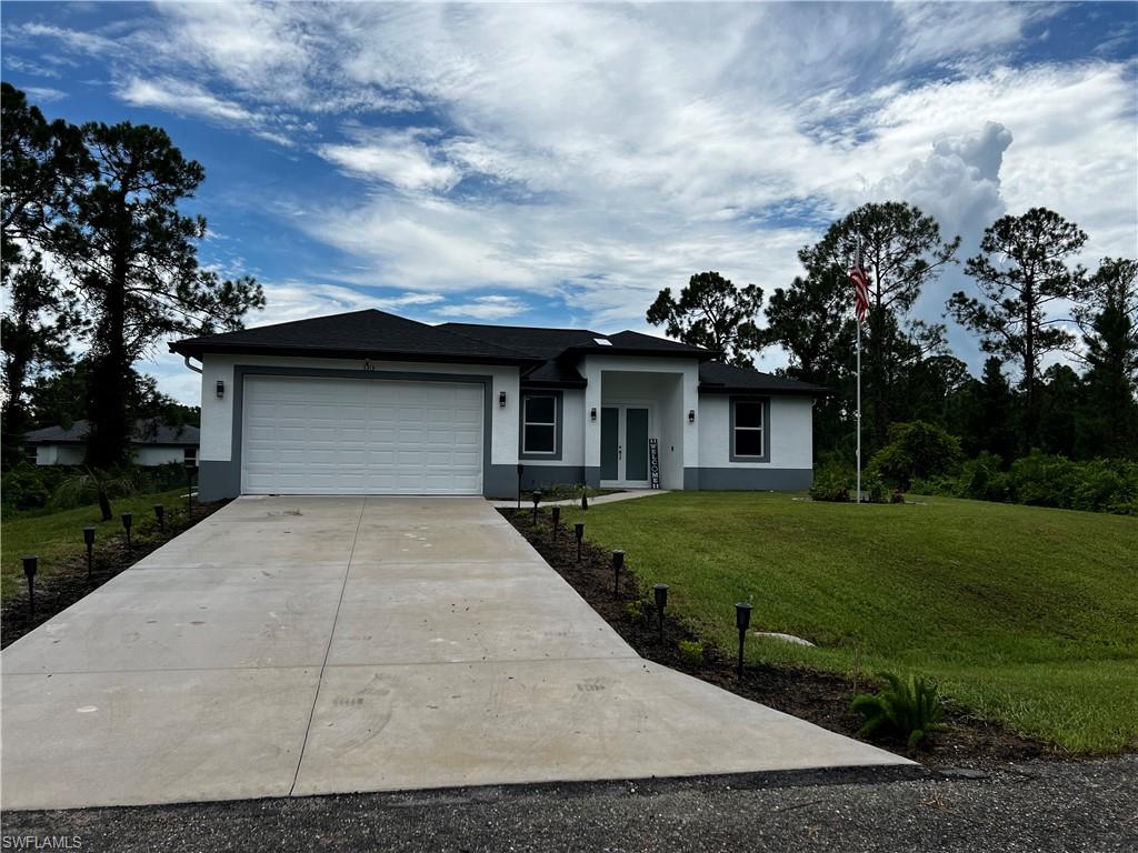 3313 68th Street West Lehigh Acres, FL 33971 - Photo 2 of 26 View of front facade with an attached garage, driveway, a front yard, and stucco siding