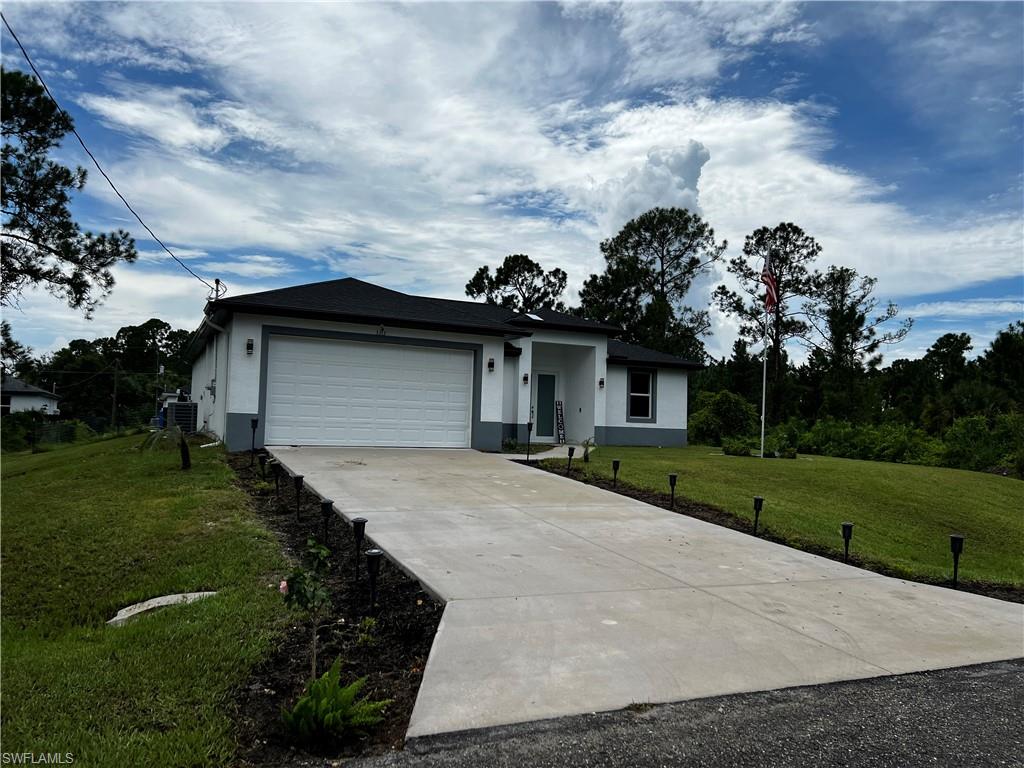 3313 68th Street West Lehigh Acres, FL 33971 - Photo 3 of 26 Single story home with stucco siding, driveway, cooling unit, an attached garage, and a front yard
