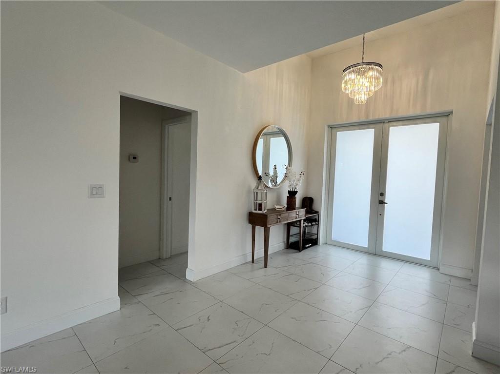 3313 68th Street West Lehigh Acres, FL 33971 - Photo 7 of 26 Foyer featuring light marble finish flooring, a chandelier, and french doors