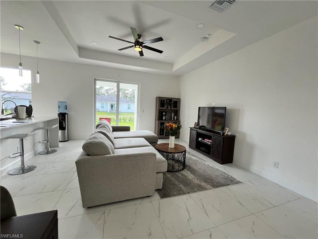 3313 68th Street West Lehigh Acres, FL 33971 - Photo 9 of 26 Living room with visible vents, baseboards, a raised ceiling, a ceiling fan, and marble finish floor