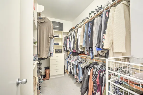 a view of walk in closet with clothes and shoes