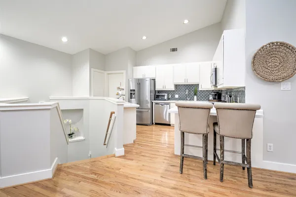 a kitchen with stainless steel appliances a refrigerator a stove a sink dishwasher and white cabinets with wooden floor