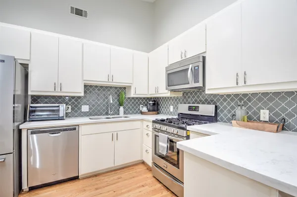 a kitchen with cabinets appliances a sink and a counter top space