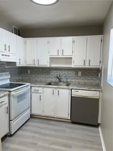 a kitchen with granite countertop white cabinets and white appliances
