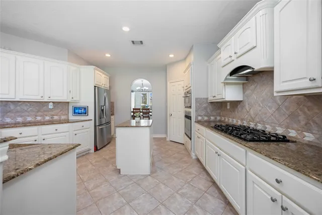 a kitchen with stainless steel appliances granite countertop a stove a sink and a refrigerator