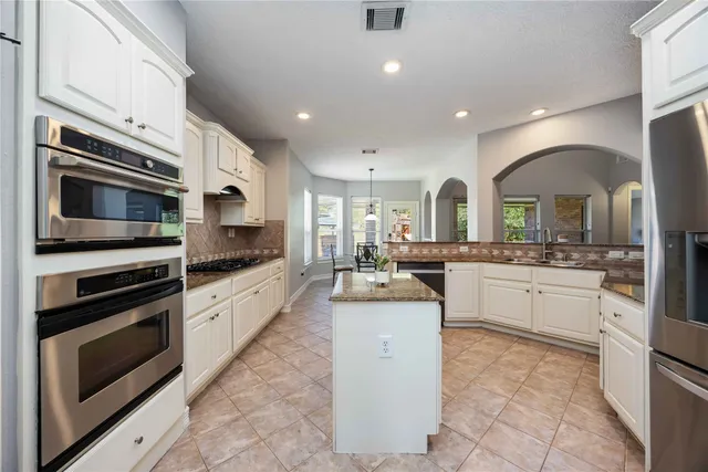 a kitchen with stainless steel appliances kitchen island granite countertop a stove top oven and sink
