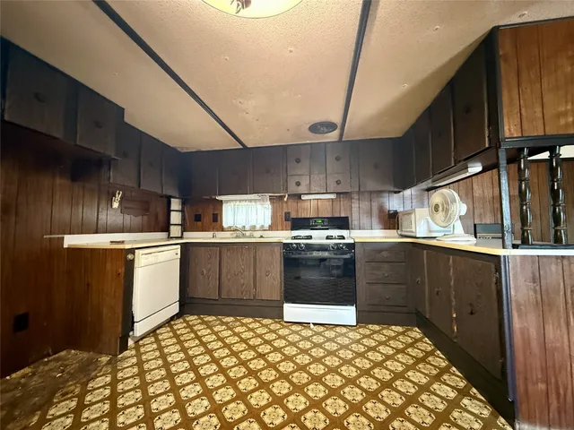 a kitchen with granite countertop a refrigerator and a stove top oven