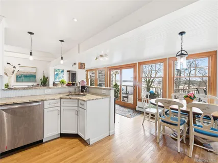 a open kitchen with stainless steel appliances granite countertop a stove top oven a dining table and chairs with wooden floor