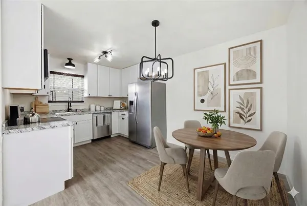 a kitchen with stainless steel appliances a dining table chairs and wooden floor