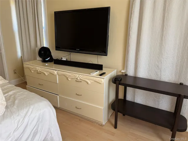 a bedroom with a bed and a flat tv screen on a dresser