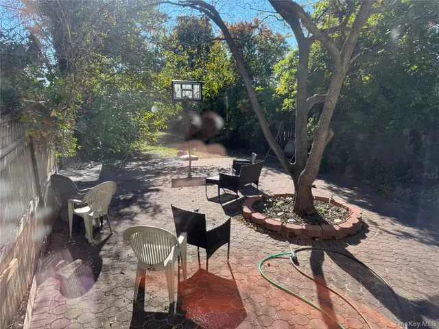 a view of a backyard with table and chairs potted plants and large tree