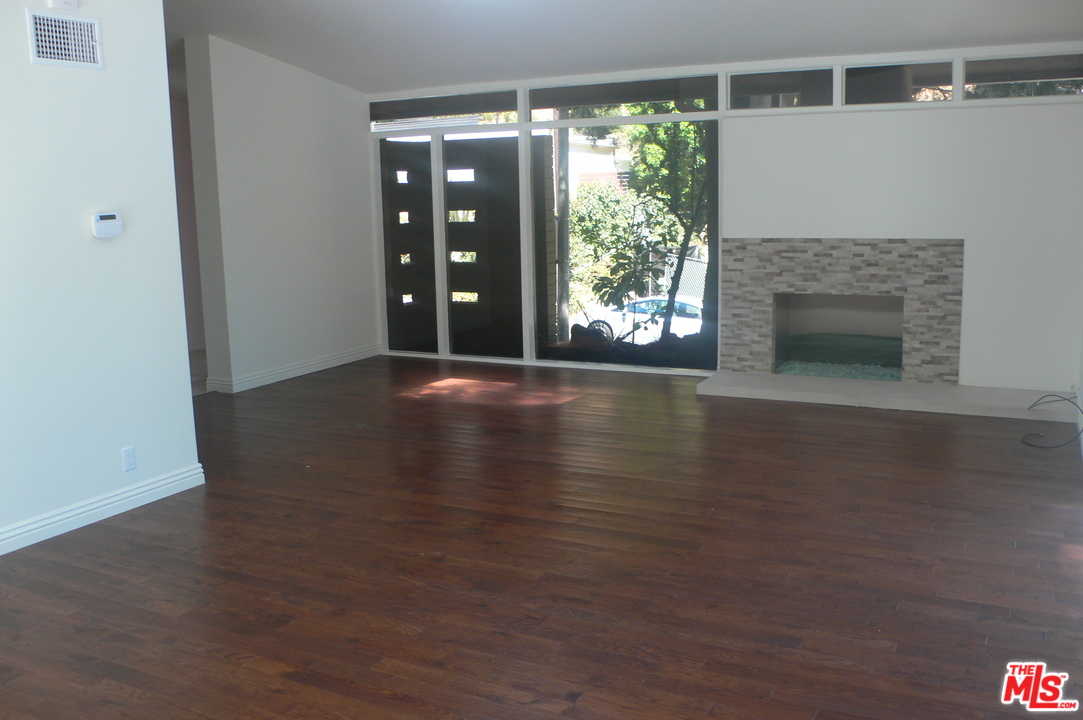 2101 Roscomare Road Los Angeles, CA 90077 - Photo 2 of 8 a view of a livingroom with wooden floor a fireplace and windows