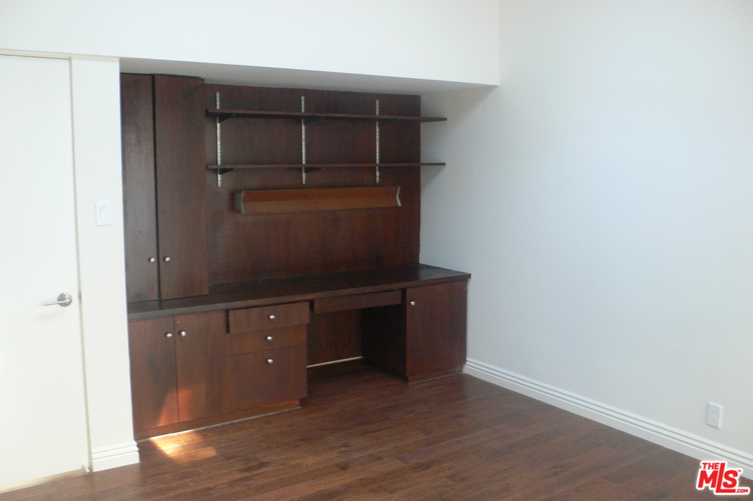 2101 Roscomare Road Los Angeles, CA 90077 - Photo 4 of 8 an empty room with wooden floor and cabinet
