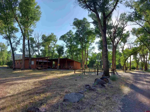 a view of a house with a big yard and large trees