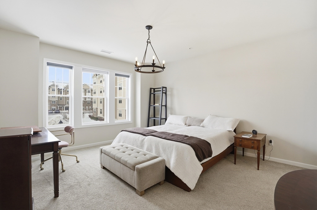 2306 Talbot Way, Unit 2306 Westborough, MA 01581 - Photo 12 of 37 a bedroom with a bed a table and chair