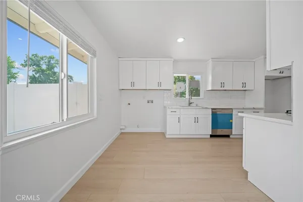 a kitchen with white cabinets and window