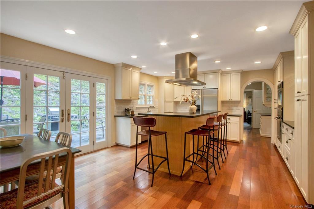 a dining room with stainless steel appliances kitchen island granite countertop a dining table chairs and large windows