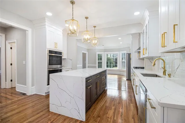 a large kitchen with granite countertop a large stove a sink dishwasher and white cabinets with wooden floor