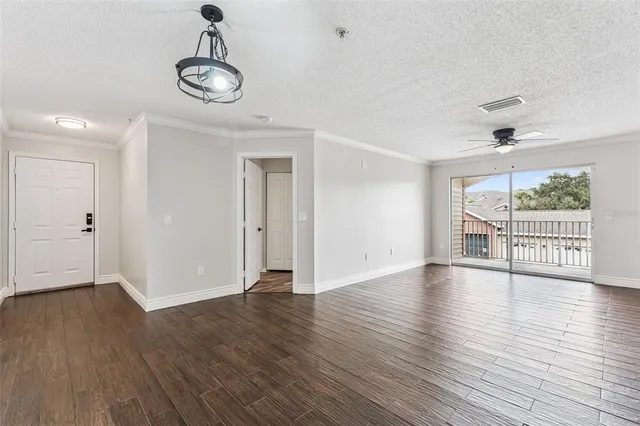 a view of an empty room with wooden floor and window