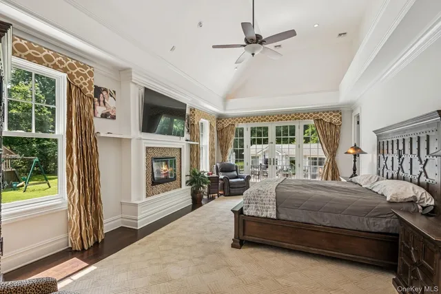 a bedroom with a large bed flat screen tv and a fireplace