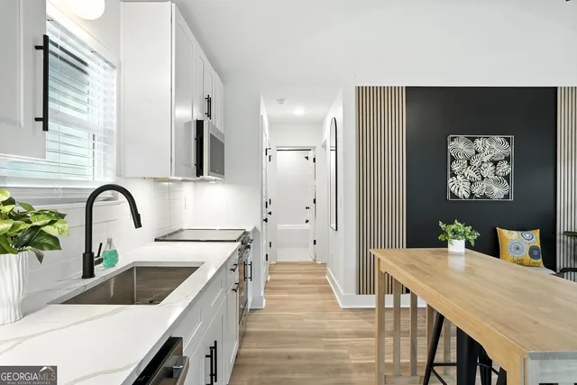 a kitchen with stainless steel appliances a stove a sink dishwasher and refrigerator with wooden floor