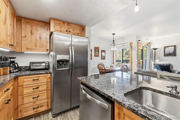 a kitchen with stainless steel appliances granite countertop a sink a refrigerator and wooden cabinets