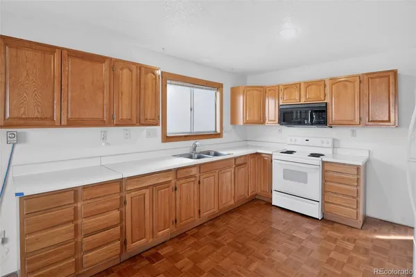a kitchen with granite countertop a sink cabinets stainless steel appliances and a window