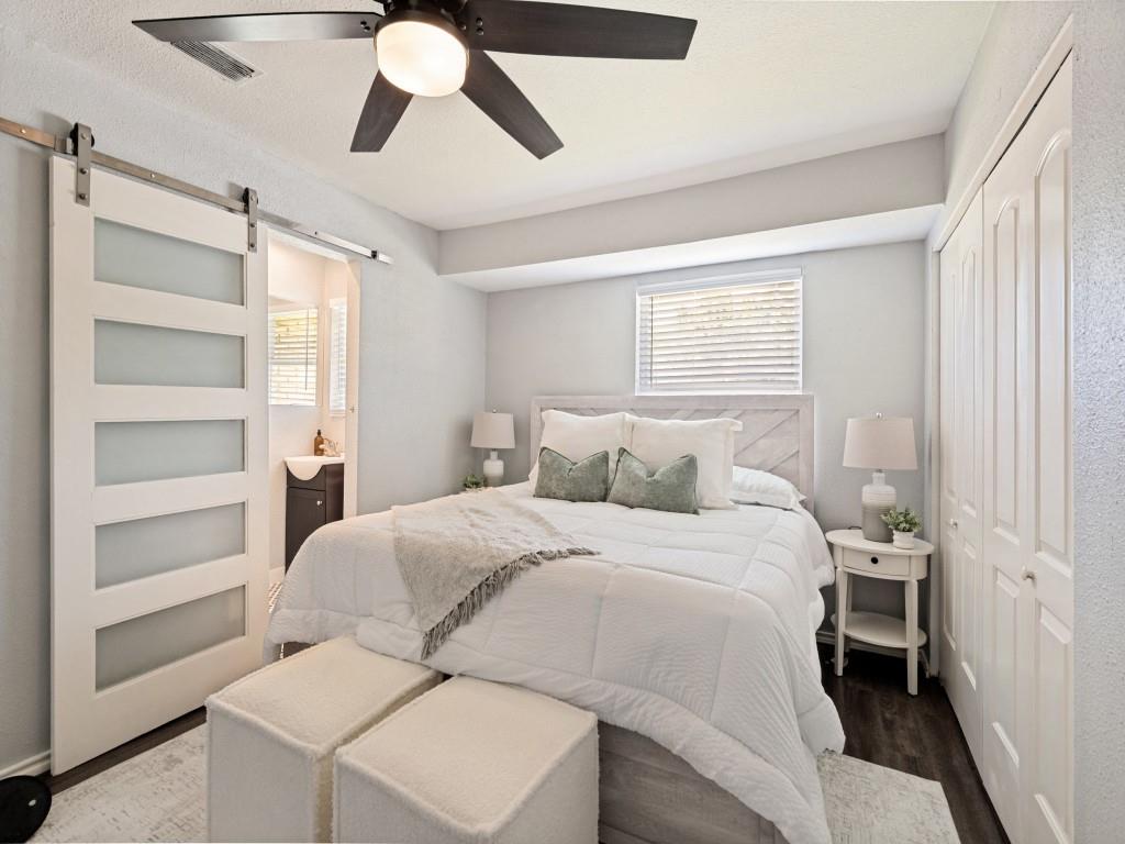 1405 Rambler Road Arlington, TX 76014 - Photo 17 of 26 Bedroom featuring a modern barn door with frosted glass panels, wood-finish flooring, a ceiling fan with integrated lighting, and bi-fold closet doors