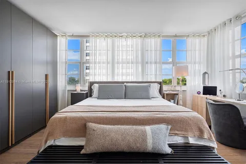 a bedroom with a bed and a potted plant on the dresser
