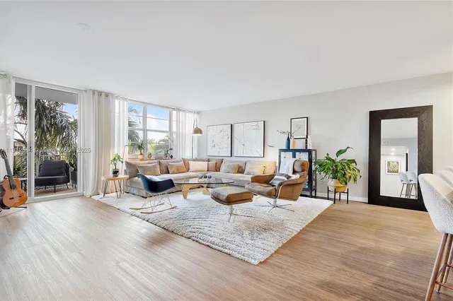 a living room with furniture floor to ceiling window and wooden floor
