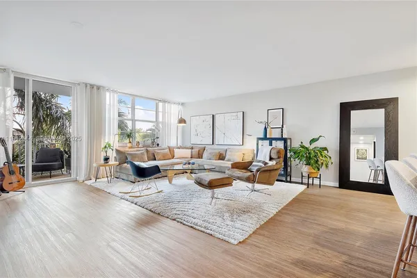 a living room with furniture floor to ceiling window and wooden floor