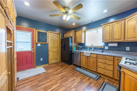 a kitchen with stainless steel appliances granite countertop a refrigerator a sink dishwasher a stove and white countertops with wooden floor