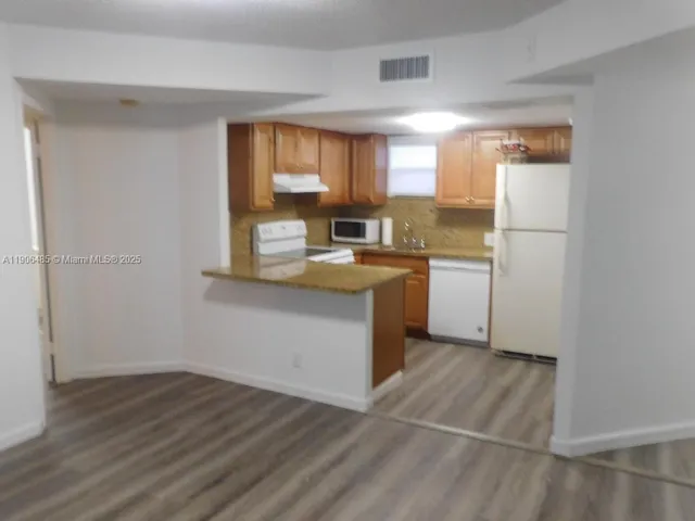 a kitchen with a sink cabinets and wooden floor