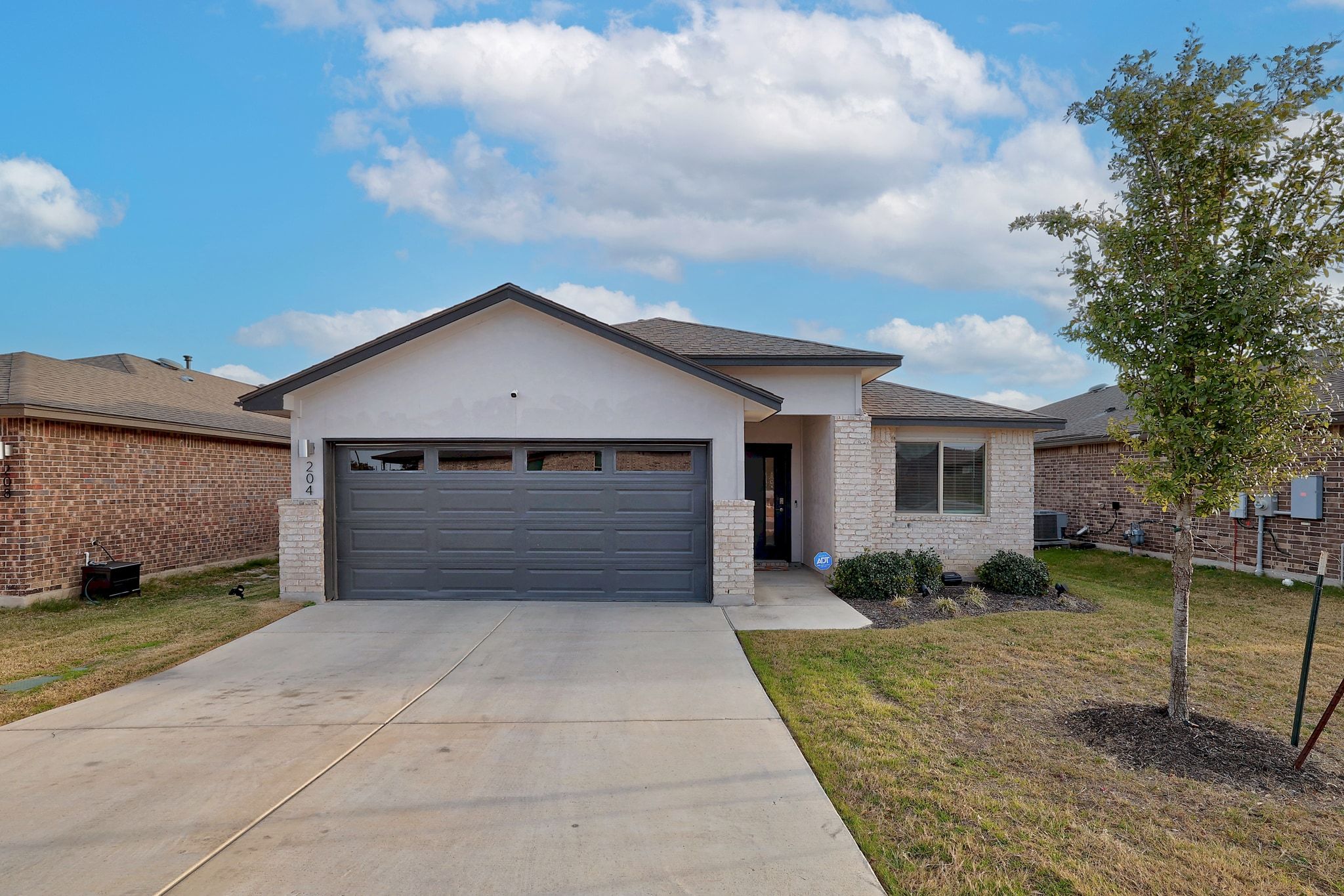 204 Halford Road Georgetown, TX 78633 - Photo 2 of 27 Single story home featuring a front yard, stucco siding, concrete driveway, an attached garage, and brick siding