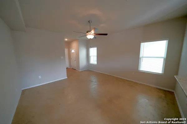 an empty room with windows and chandelier fan