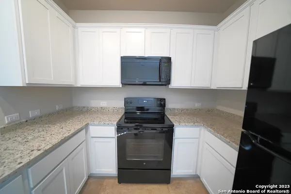 a kitchen with granite countertop white cabinets and a stove top oven