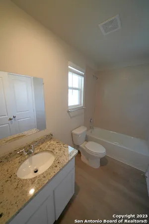 a bathroom with a granite countertop sink and a toilet