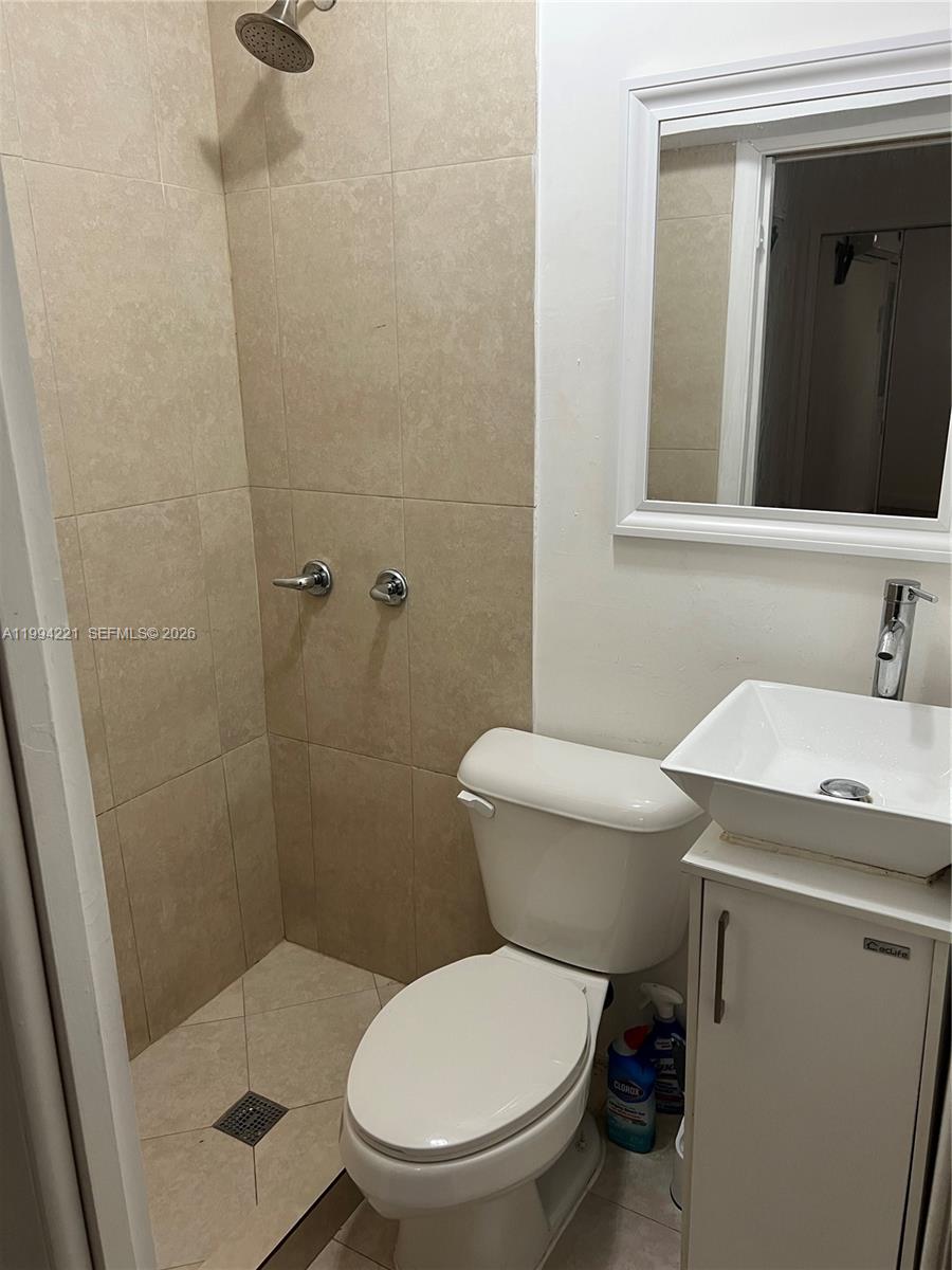 14880 Southwest 56th Terrace, Unit 3 Miami, FL 33193 - Photo 7 of 8 a bathroom with a granite countertop toilet a sink and a mirror