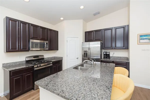 a kitchen with granite countertop stainless steel appliances a stove microwave and sink
