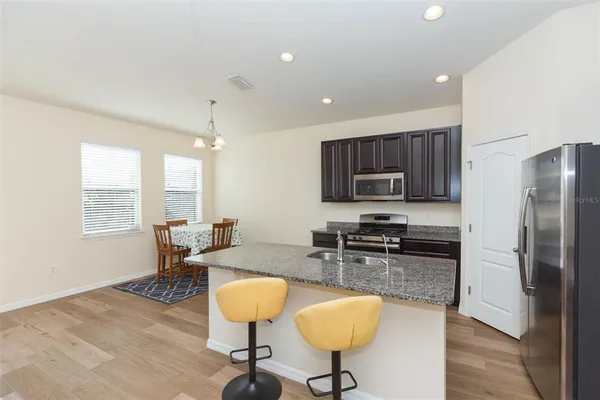 a kitchen with stainless steel appliances granite countertop a stove a refrigerator a sink a stove with island cabinets and wooden floor