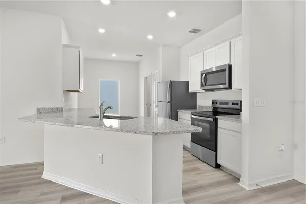 a kitchen with kitchen island granite countertop a sink stainless steel appliances and white cabinets