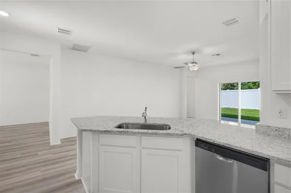 a kitchen with granite countertop a sink and a white cabinets
