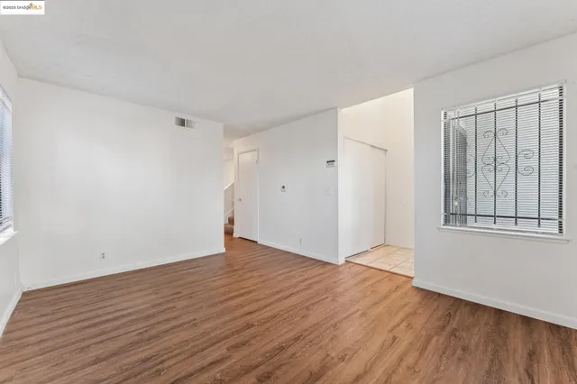 a view of an empty room with wooden floor and a window