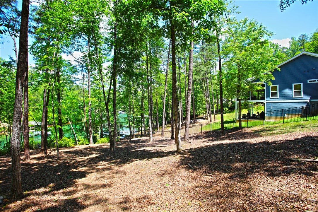 Lot 114 Harbor Point Seneca, SC 29672 - Photo 36 of 46 This serene woodland property offers a peaceful retreat with lake access and a charming blue residence.
