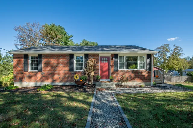 a view of a house with a yard potted plants and a table