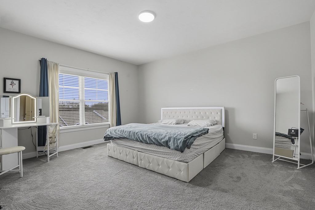 52 Logans Run, Unit 52 Millbury, MA 01527 - Photo 24 of 41 a spacious bedroom with a bed and a table in it