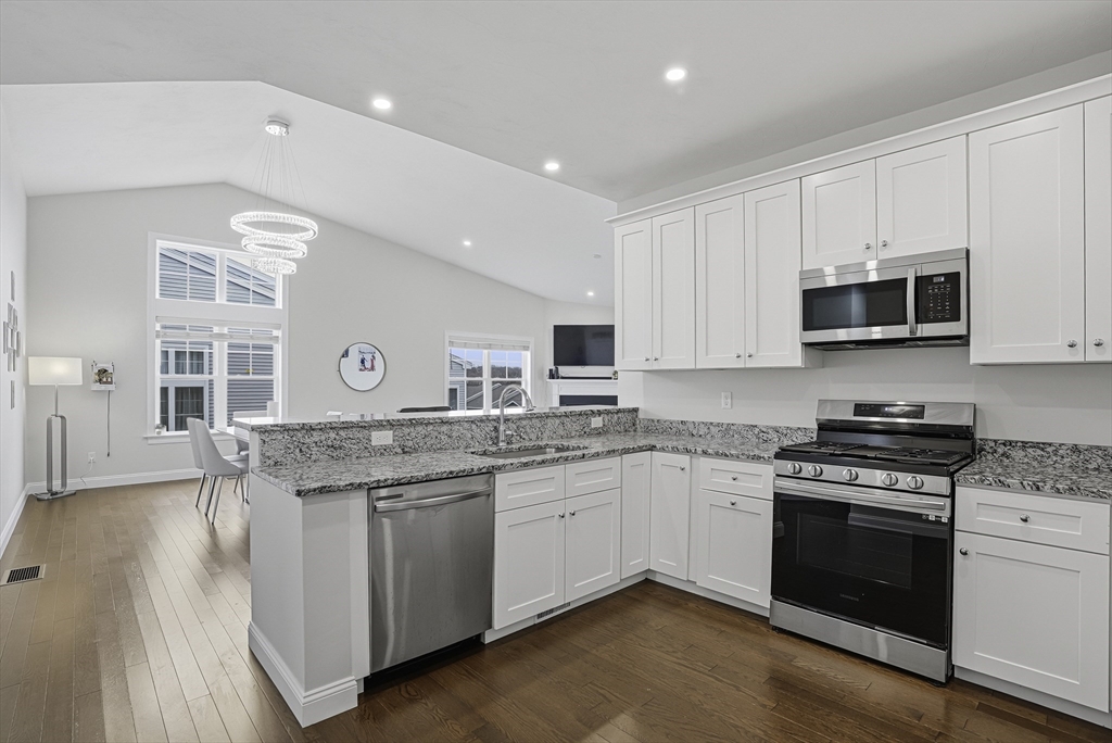 52 Logans Run, Unit 52 Millbury, MA 01527 - Photo 5 of 41 a kitchen with stainless steel appliances granite countertop a stove top oven a sink dishwasher and white cabinets with wooden floor