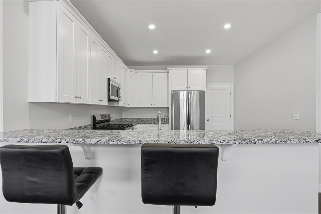 52 Logans Run, Unit 52 Millbury, MA 01527 - Photo 10 of 41 a kitchen with stainless steel appliances granite countertop a sink a stove a refrigerator a microwave and cabinets