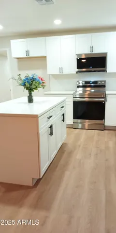 a kitchen with stainless steel appliances a stove and white cabinets